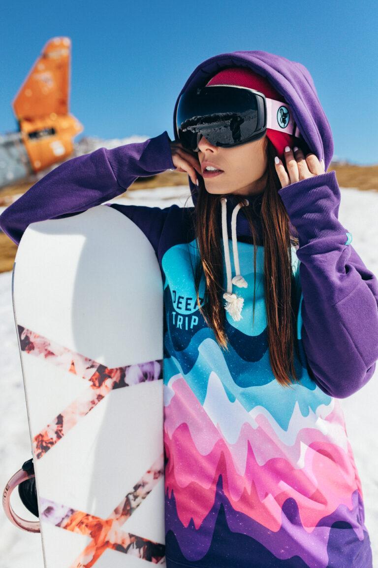 Kobieta z założonymi goglami sferycznymi i snowboardem